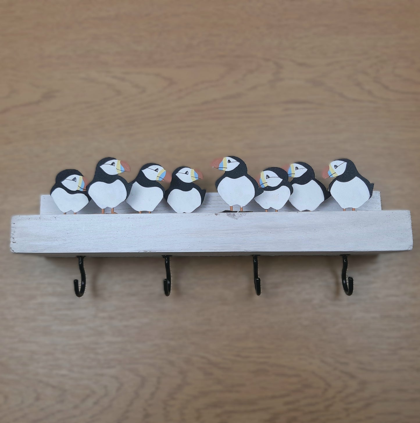 A decorative key rack with some puffins on, on a wooden background