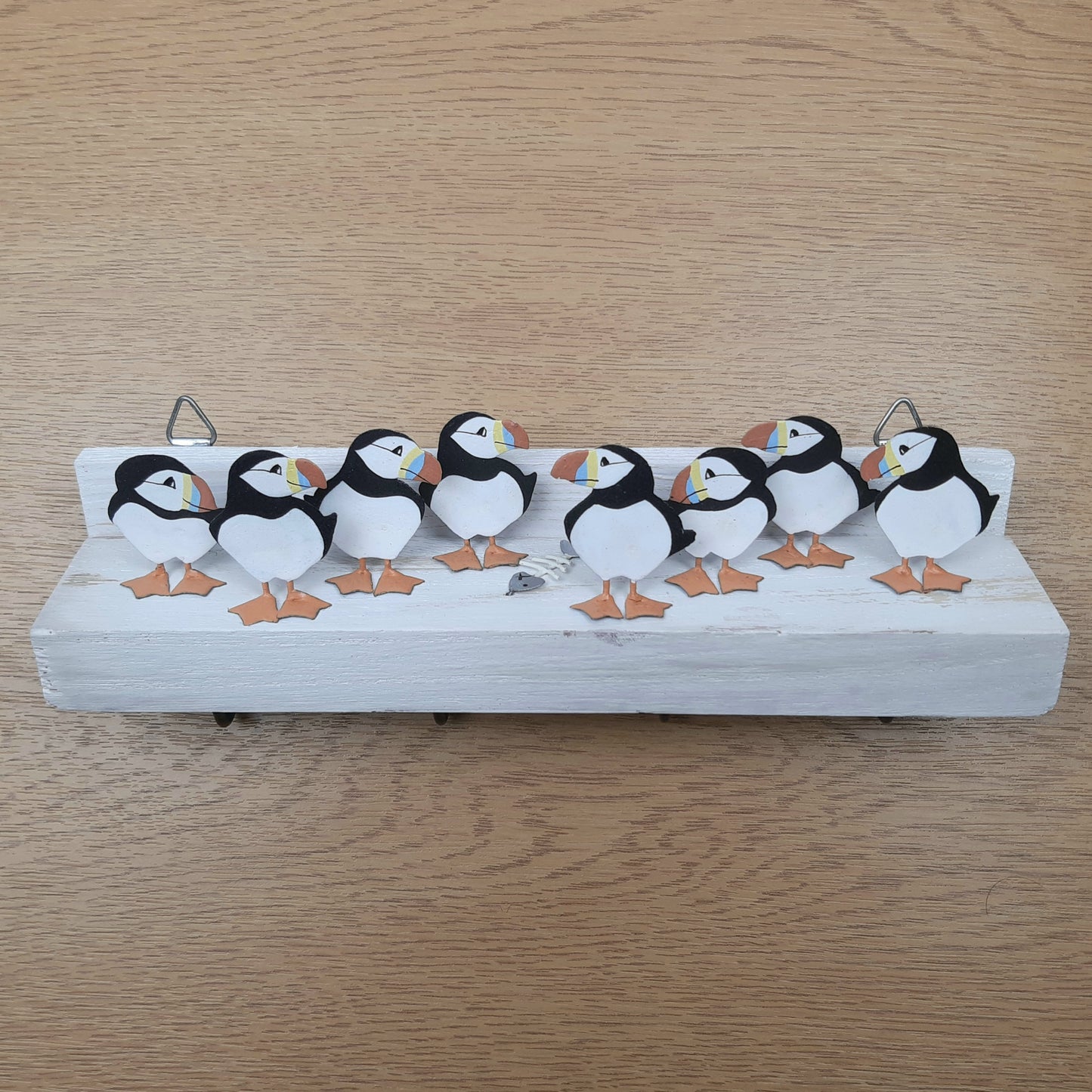 Decorative shelf with metal painted puffins and a fish skeleton on a wooden surface