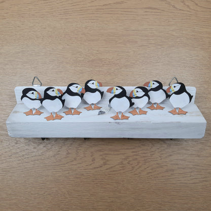 Decorative shelf with metal painted puffins and a fish skeleton on a wooden surface