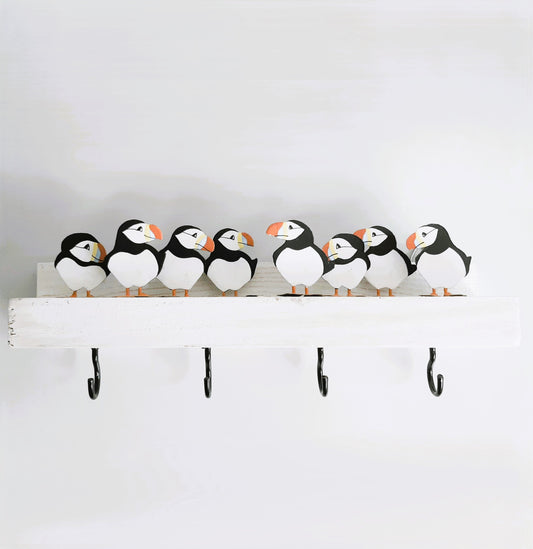 Decorative shelf with puffin-shaped figures and hooks on a plain background