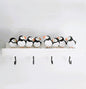 Decorative shelf with puffin-shaped figures and hooks on a plain background