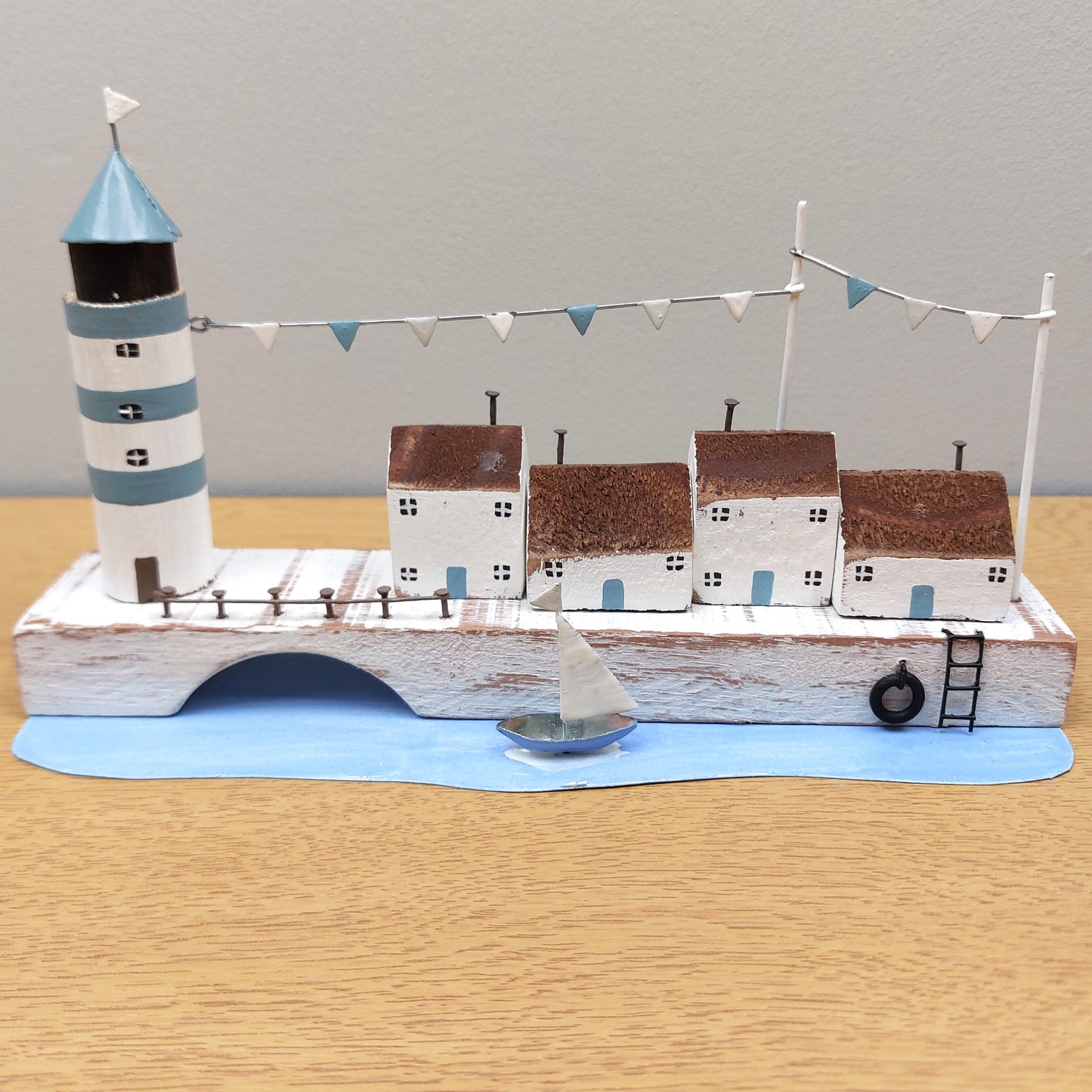 A scene depicting a lighthouse, buildings and a boat on a quayside as an ornament