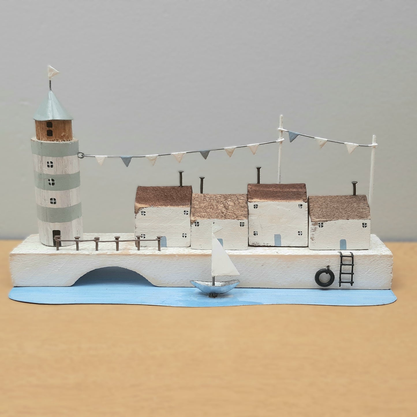 A scene depicting a lighthouse, buildings and a boat on a quayside as an ornament