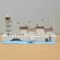 A scene depicting a lighthouse, buildings and a boat on a quayside as an ornament