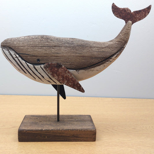 Wooden whale sculpture on a stand against a light background