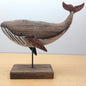 Wooden whale sculpture on a stand against a light background