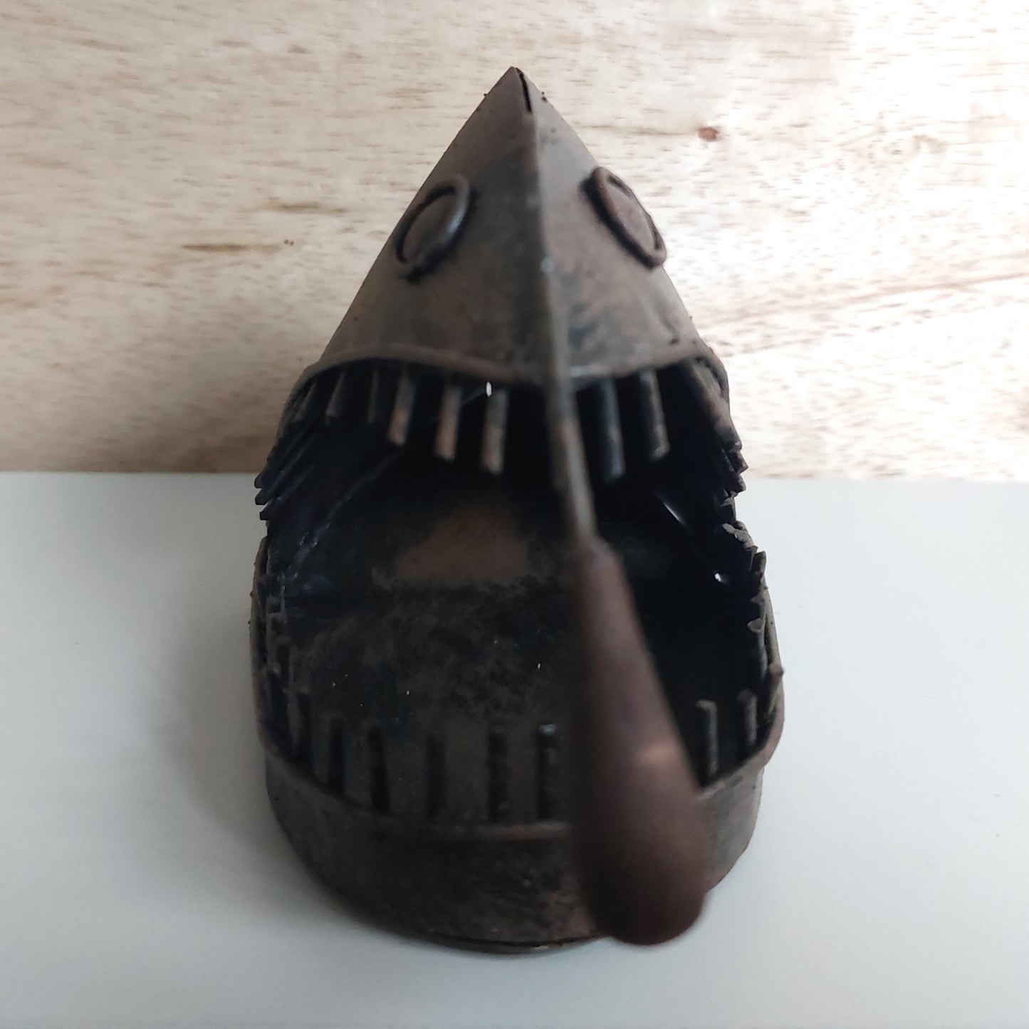 Decorative object resembling an angler fish on a light wooden surface.