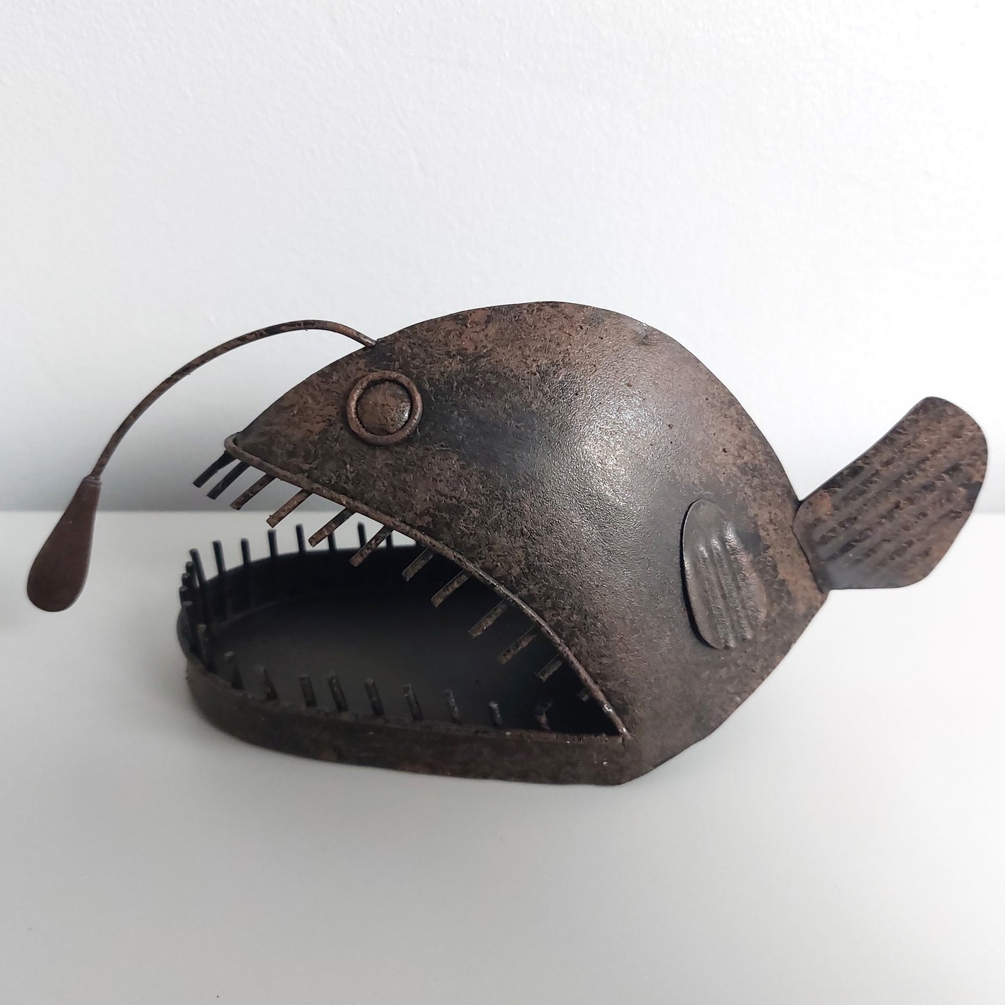 Decorative metal angler fish sculpture on a white background