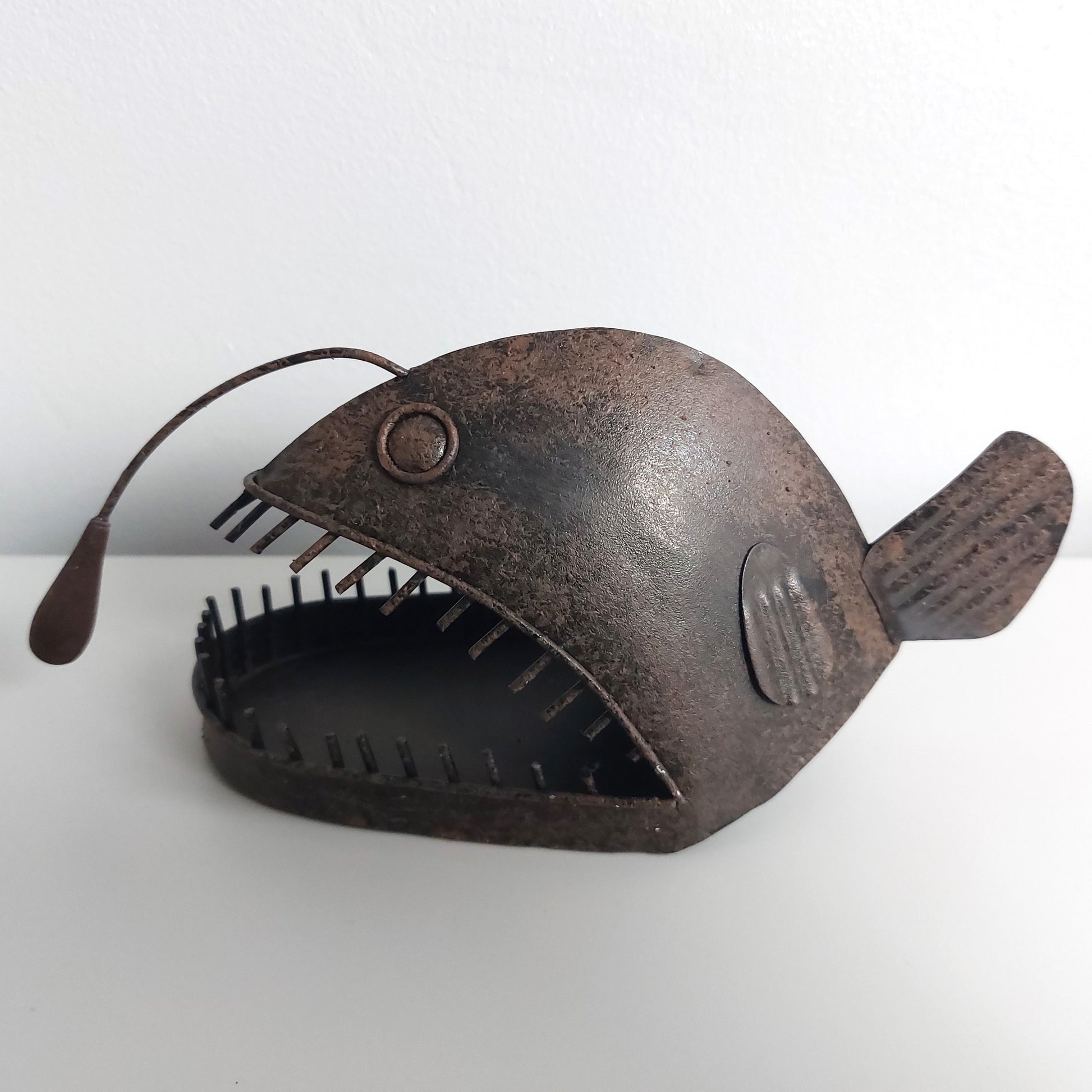 Decorative metal angler fish sculpture on a white background