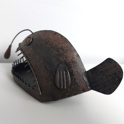 Rust-colored angler fish figurine against a pale white background