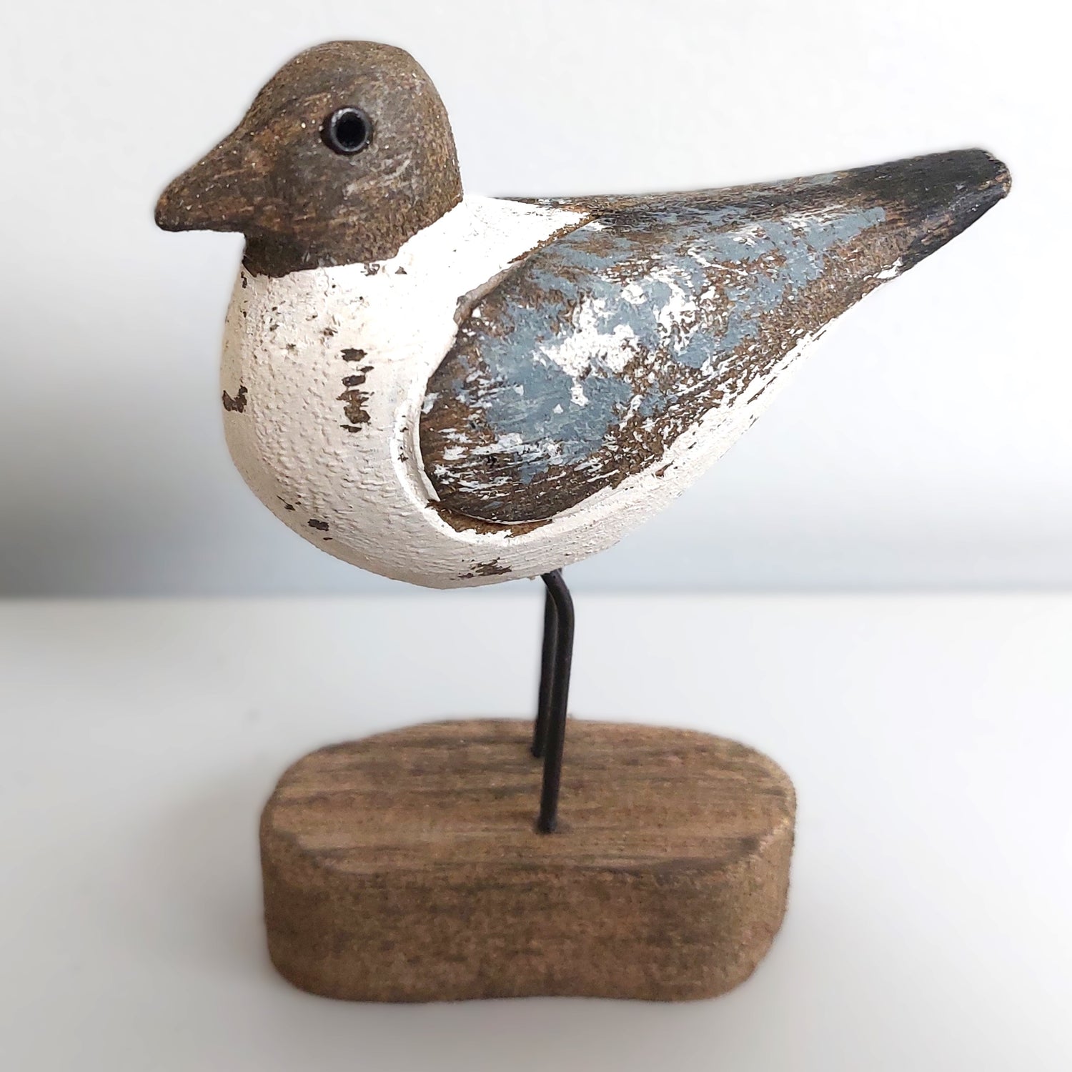 Decorative Sanderling bird figure on a wooden base against a white background