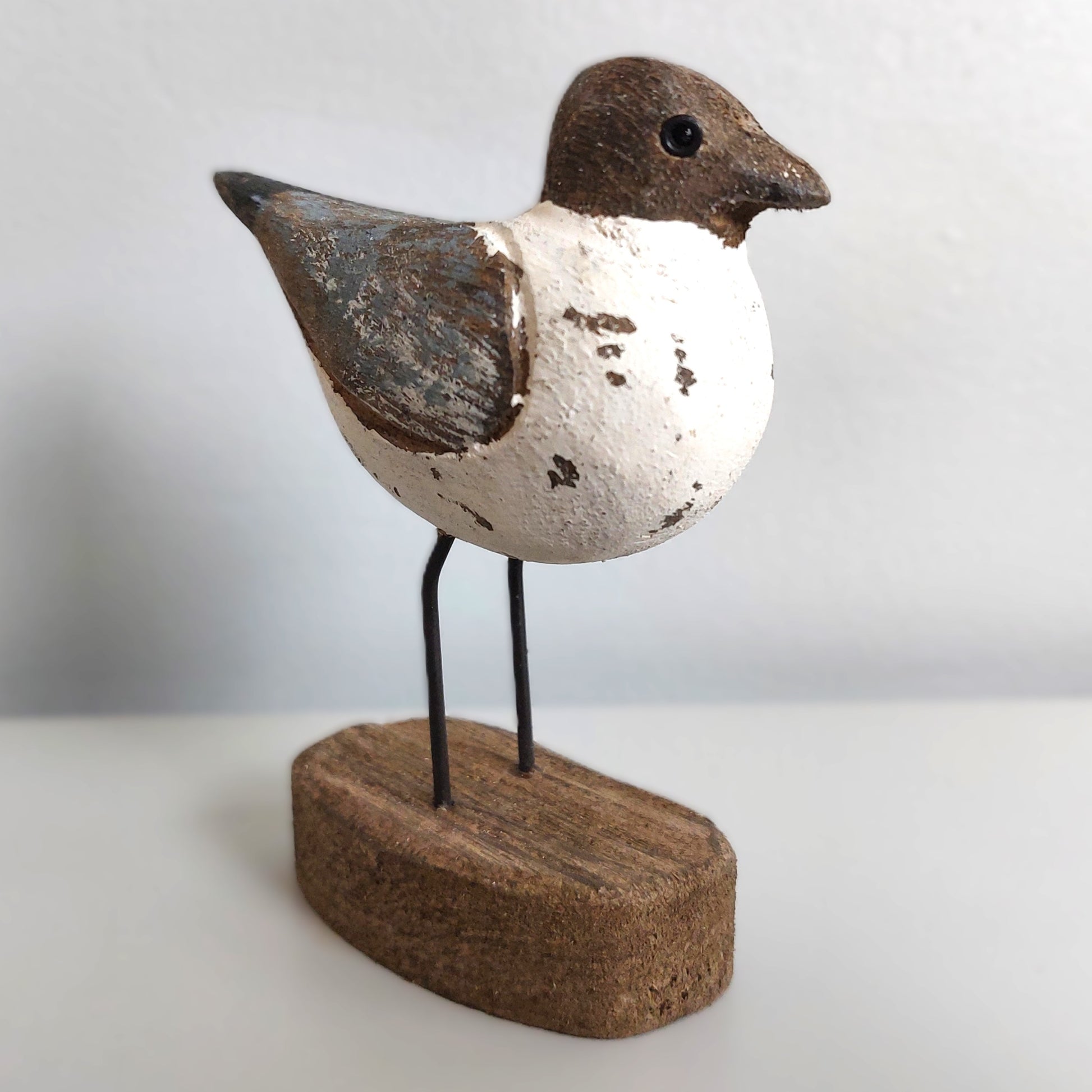 Decorative Sanderling bird sculpture on a wooden base against a plain background