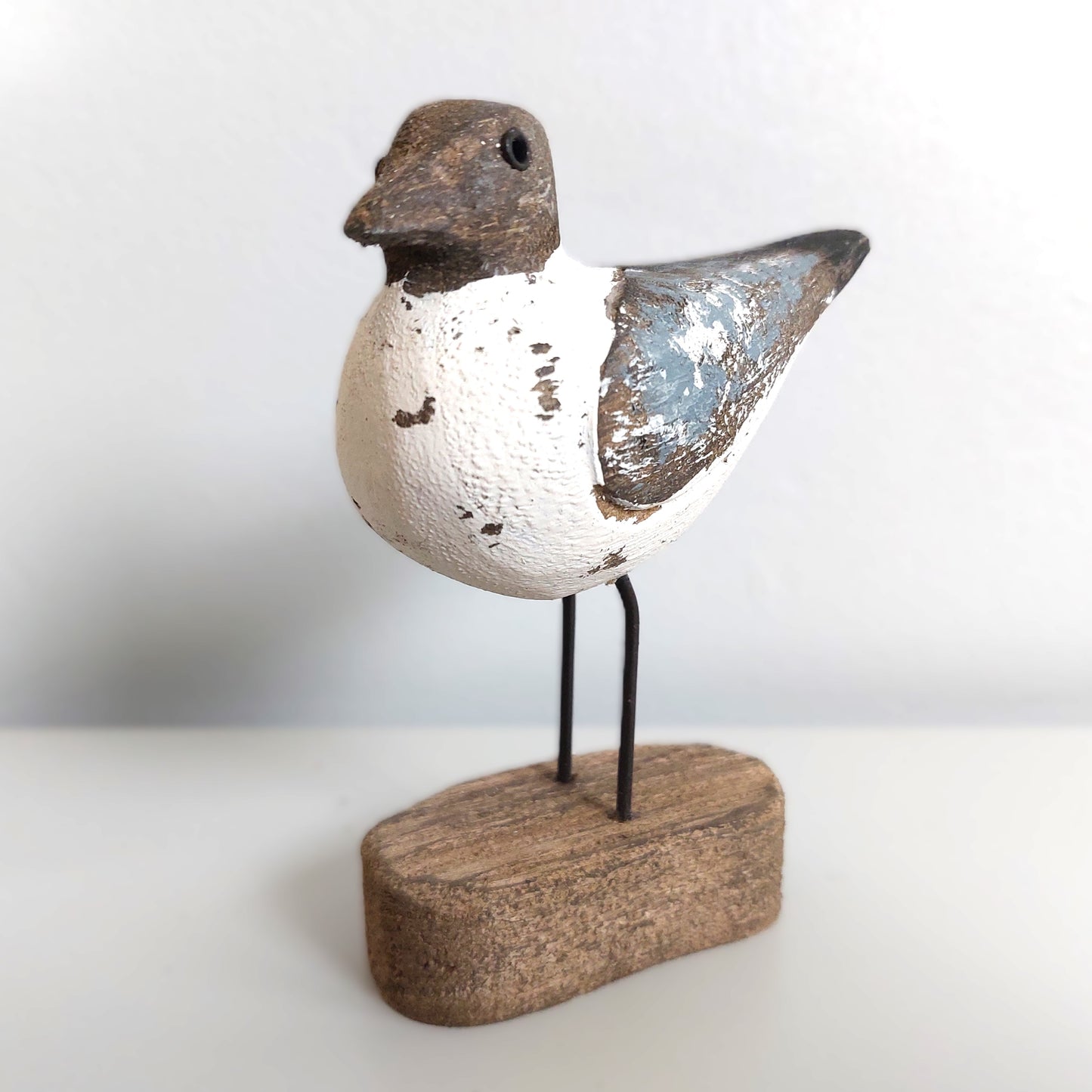 Decorative Sanderling bird figurine on a wooden base against a white background