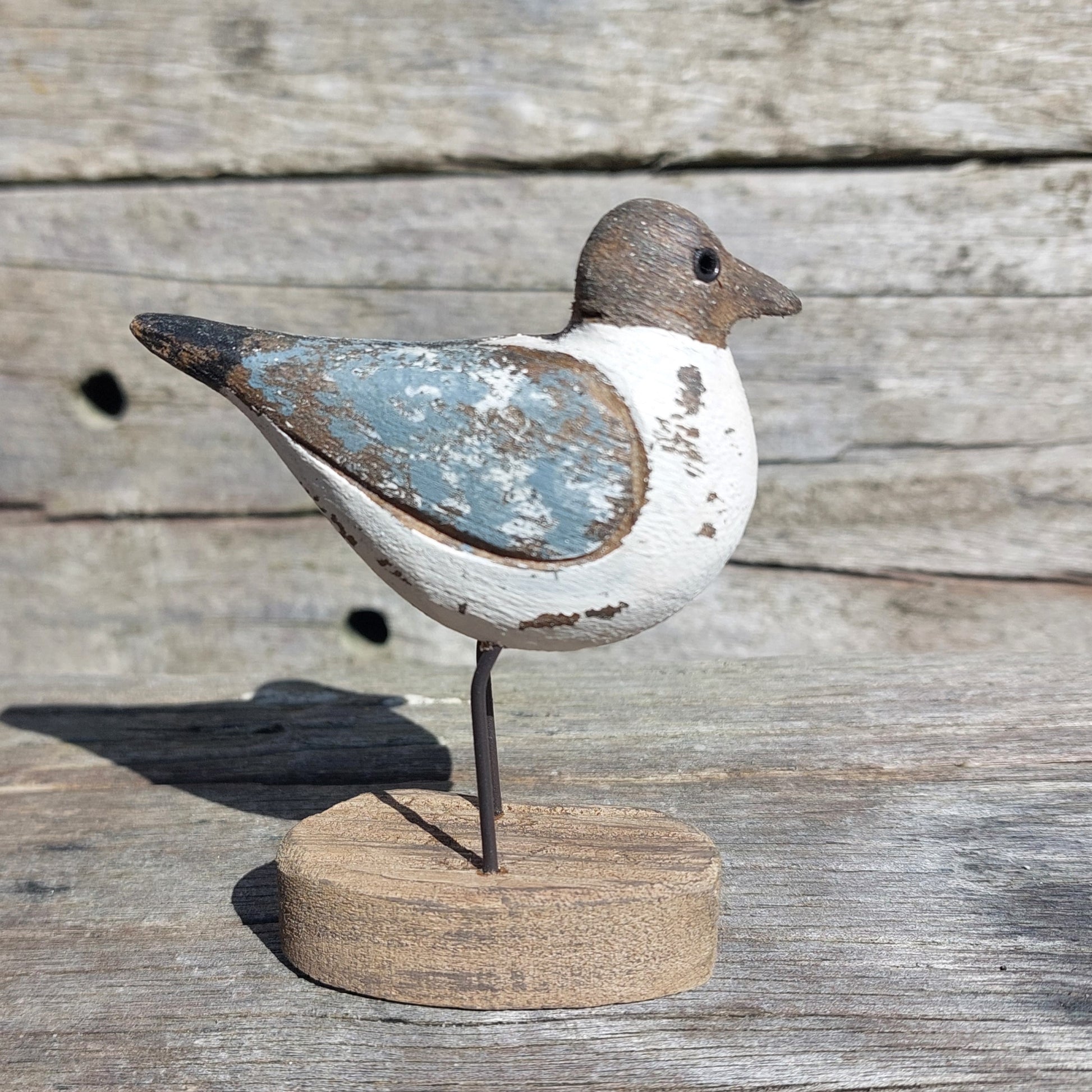 Wooden cute Sanderling bird figurine on a round base against a wooden background