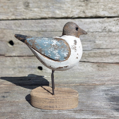 Wooden cute Sanderling bird figurine on a round base against a wooden background
