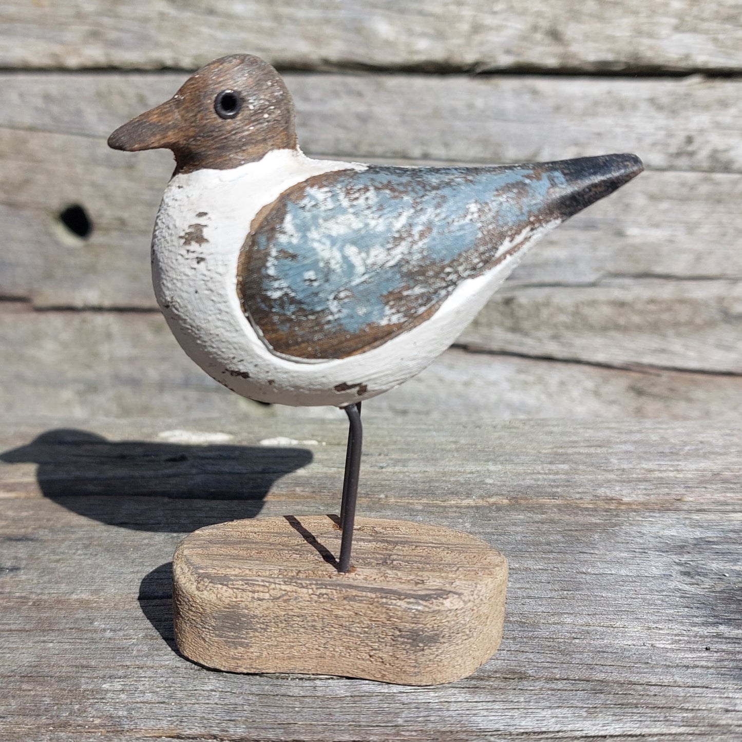 Decorative Sanderling bird figure on a stand with a rustic wooden background