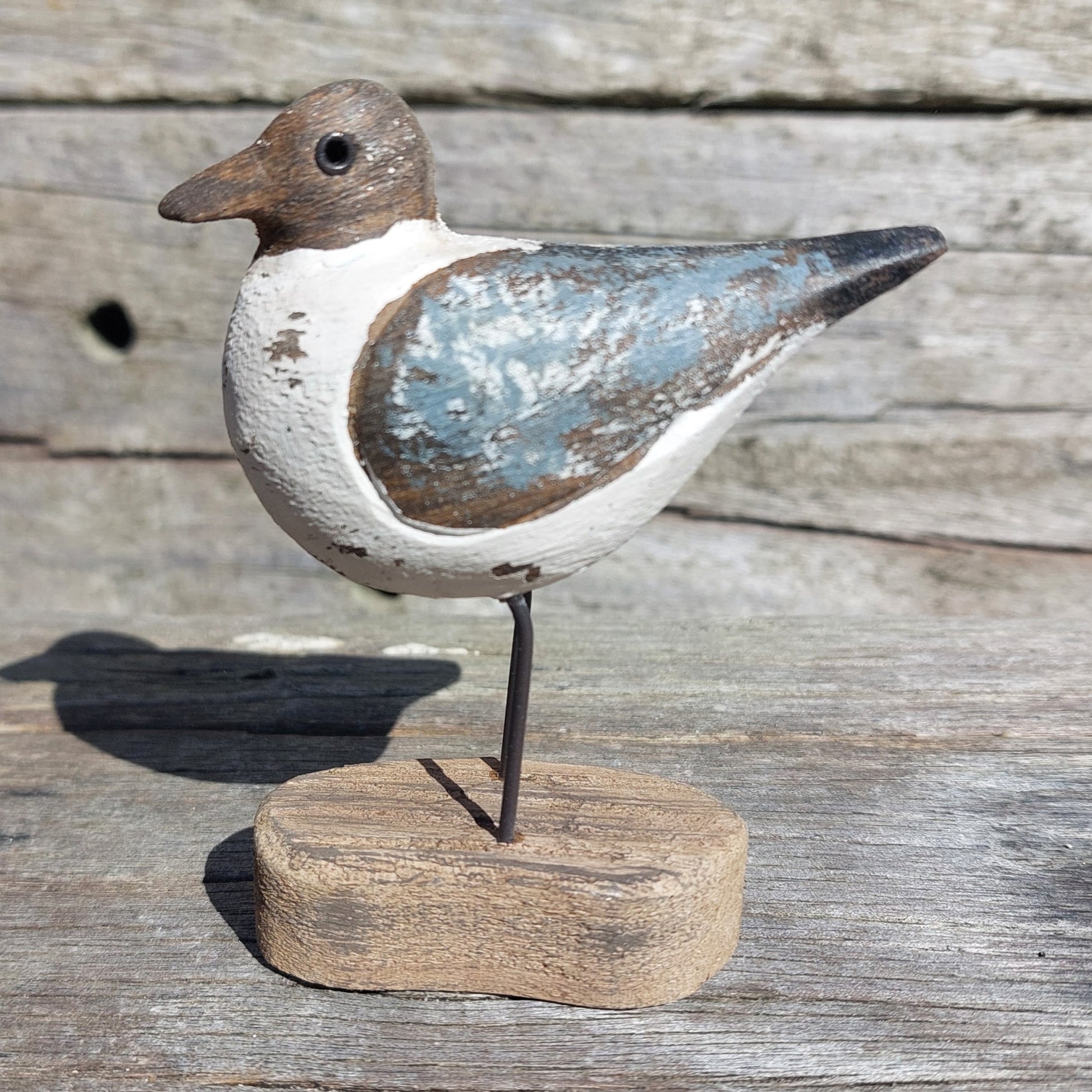 Decorative Sanderling bird figure on a stand with a rustic wooden background