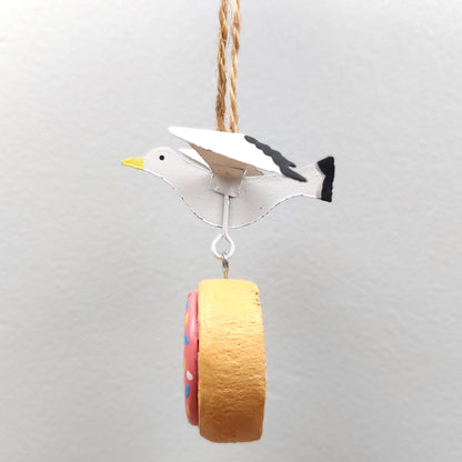 Decorative bird ornament with a colorful doughnut on a gray background