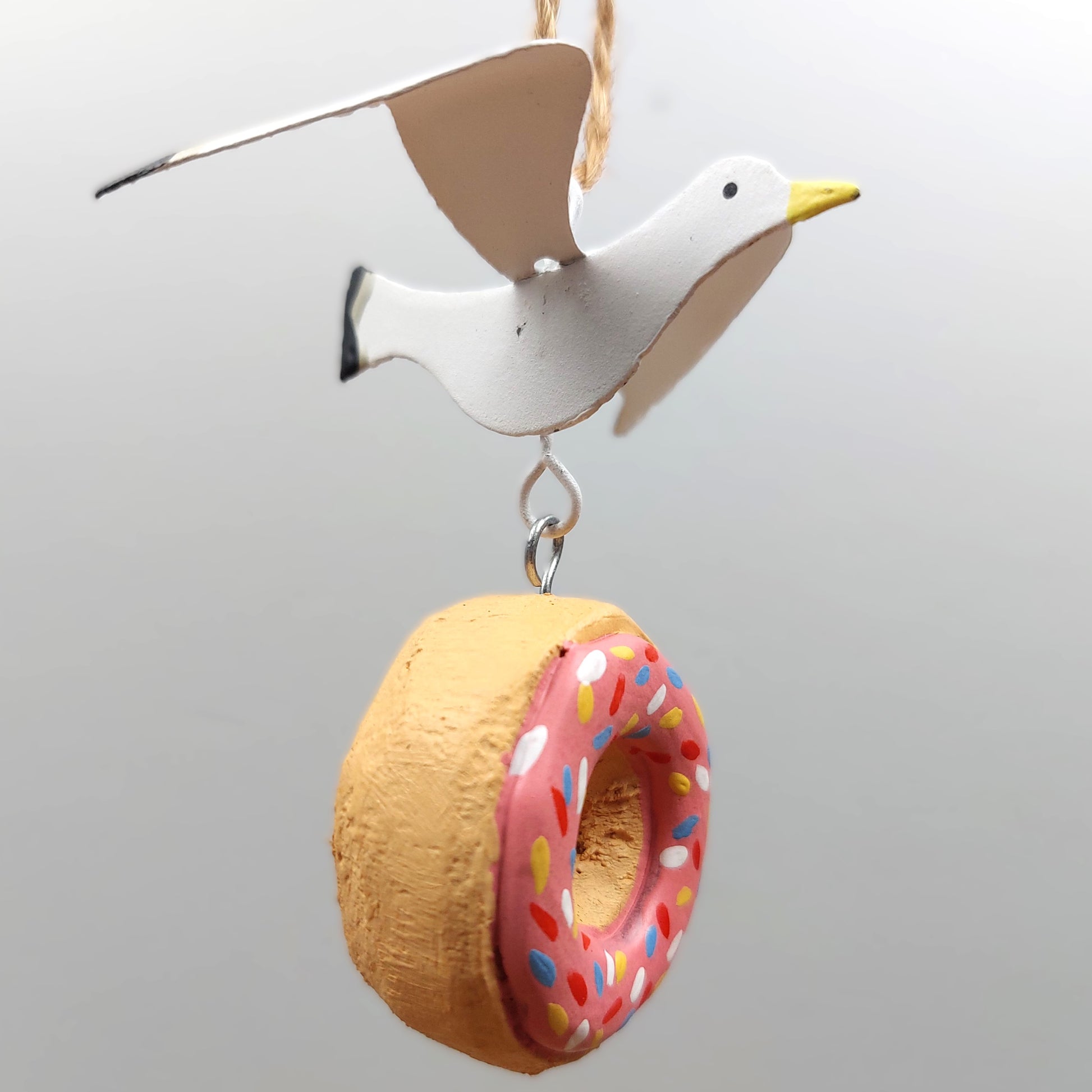 Hanging Decorative bird with a donut-shaped ring on a plain background