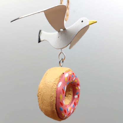Hanging Decorative bird with a donut-shaped ring on a plain background