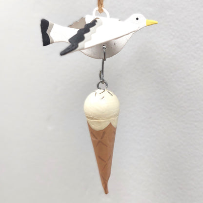 Decorative metal hanging ornament of a seagull and ice cream cone on a light gray background