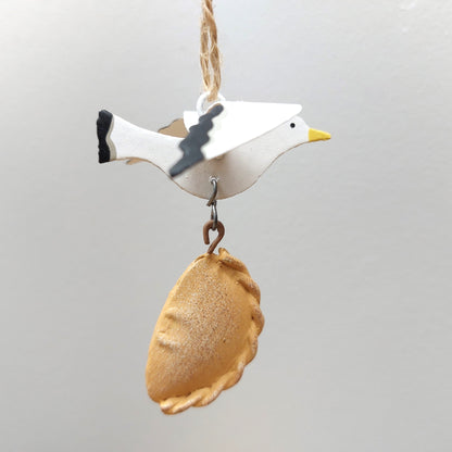 Decorative ornament of a seagull with a  pastry on a gray background