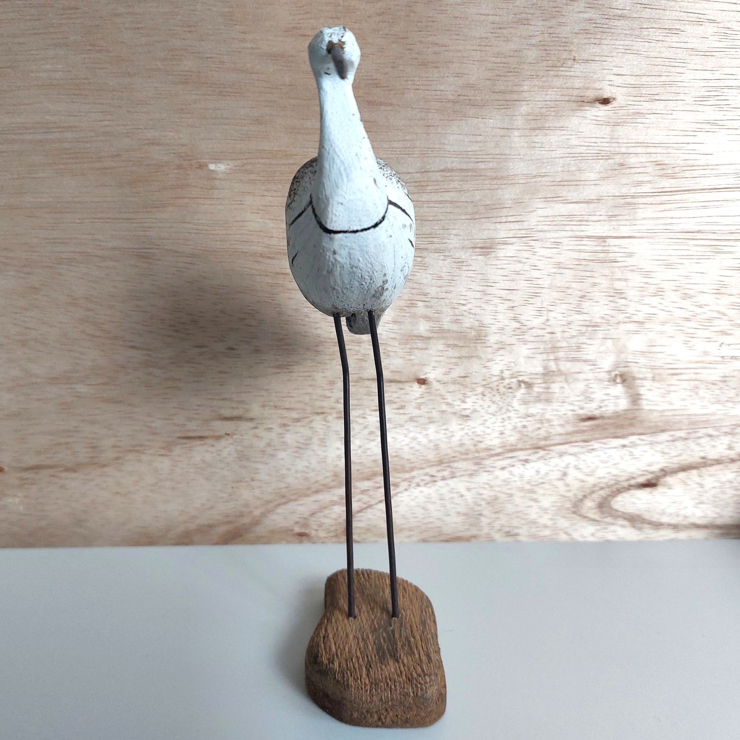 Decorative bird sculpture on a wooden base against a wooden background