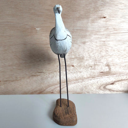Decorative bird sculpture on a wooden base against a wooden background