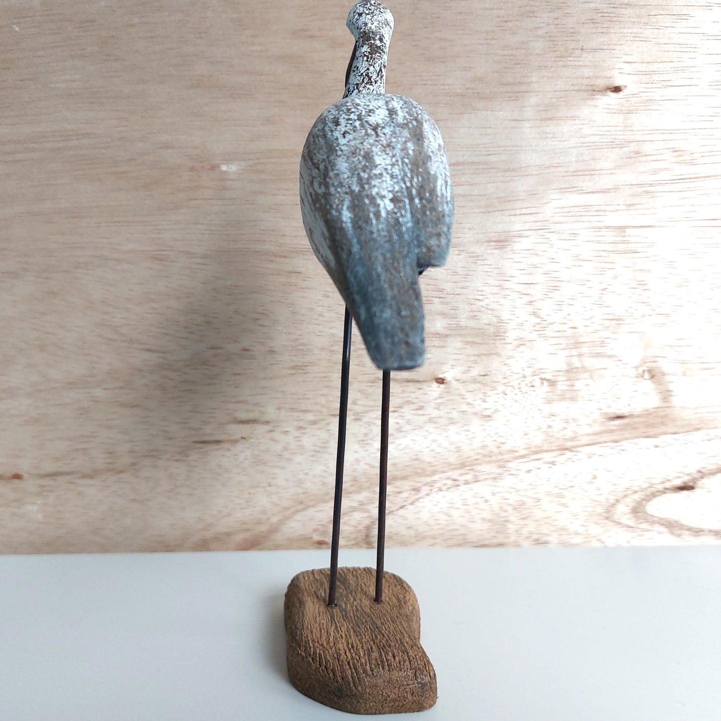 Decorative sculpture of a bird on a wooden base against a wooden background