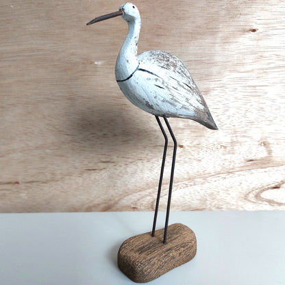 Decorative bird sculpture on a wooden base against a wooden background