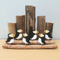 A model of 6 metal puffins with some wooden groynes and driftwood against a grey background