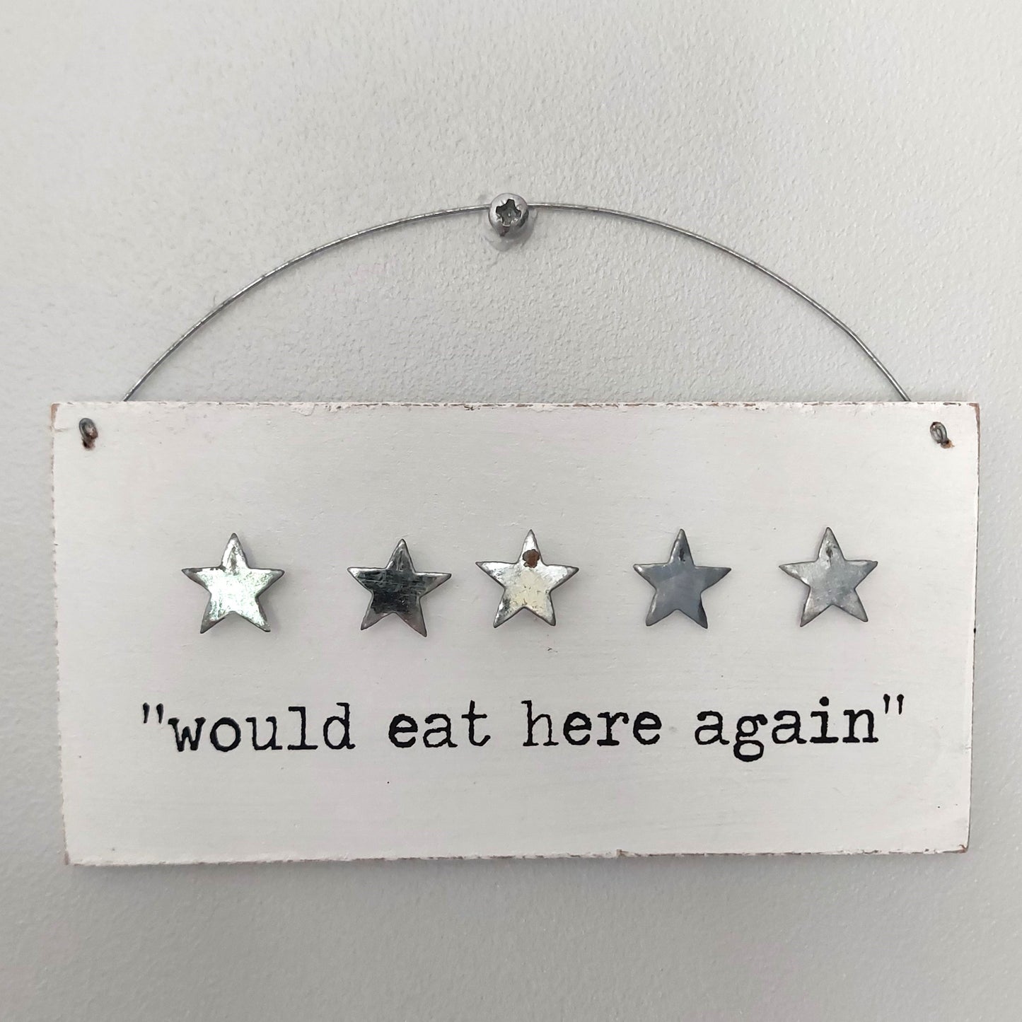 Decorative white wooden sign with five stars and text 'would eat here again' on a white background