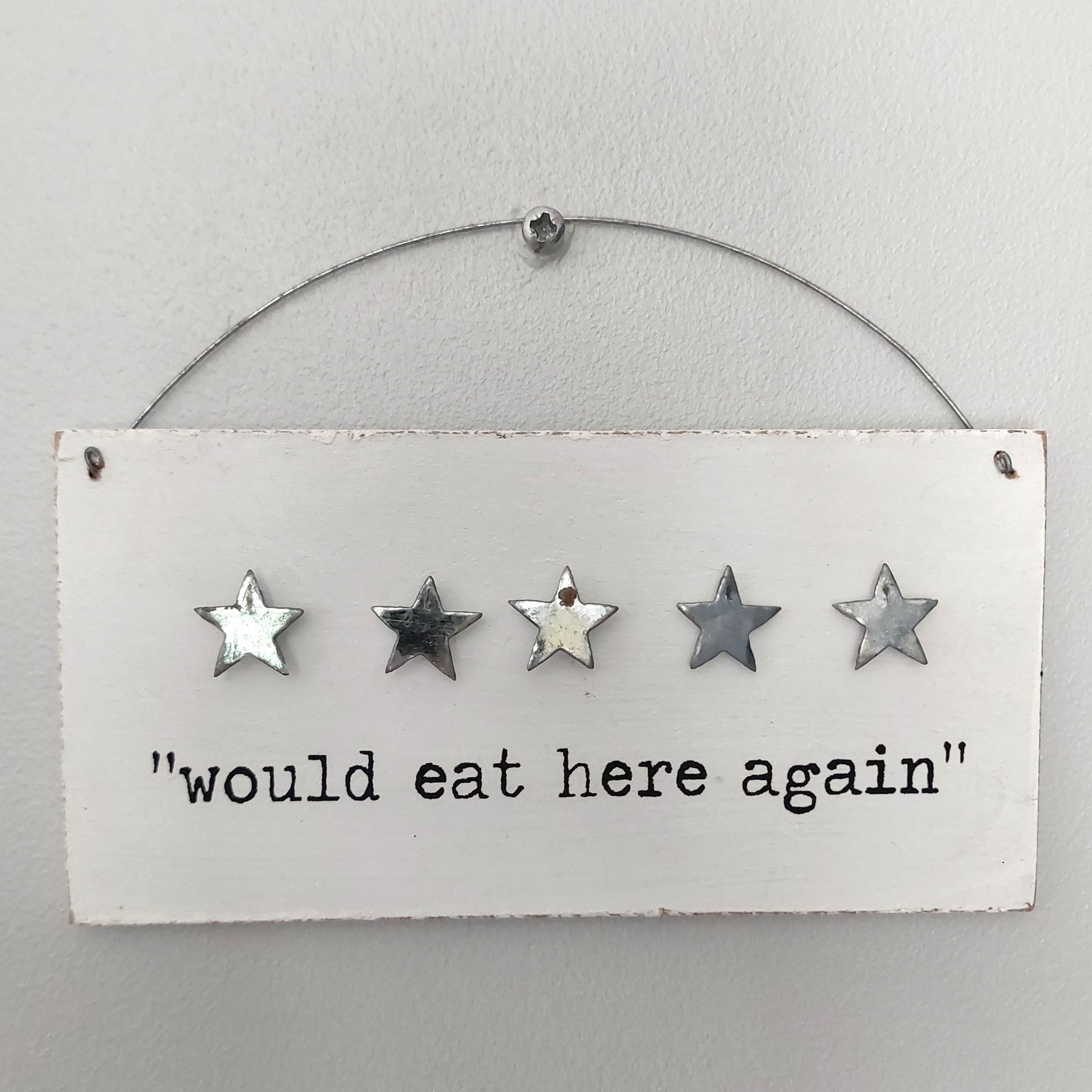 Decorative white wooden sign with five stars and text 'would eat here again' on a white background