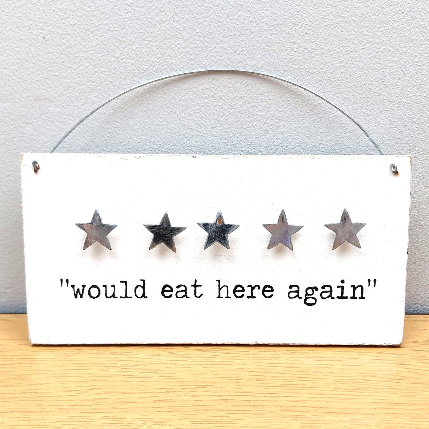 Five-star rating sign with 'would eat here again' text on a white background