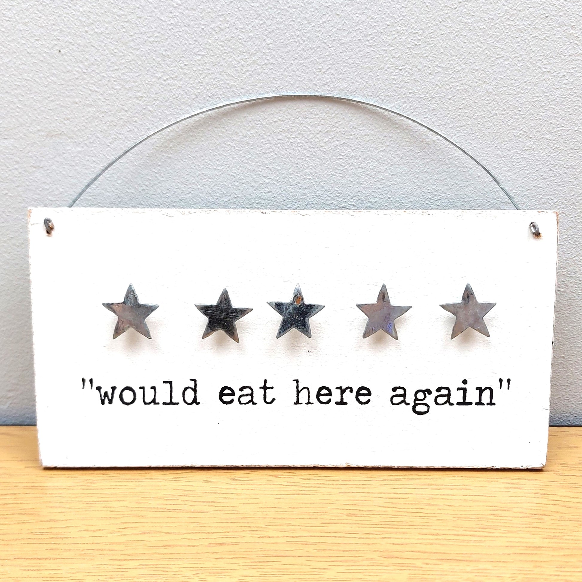 Five-star rating sign with 'would eat here again' text on a white background