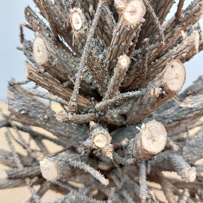 Close-up of a stick christmas tree with cut branches against a blurred natural background