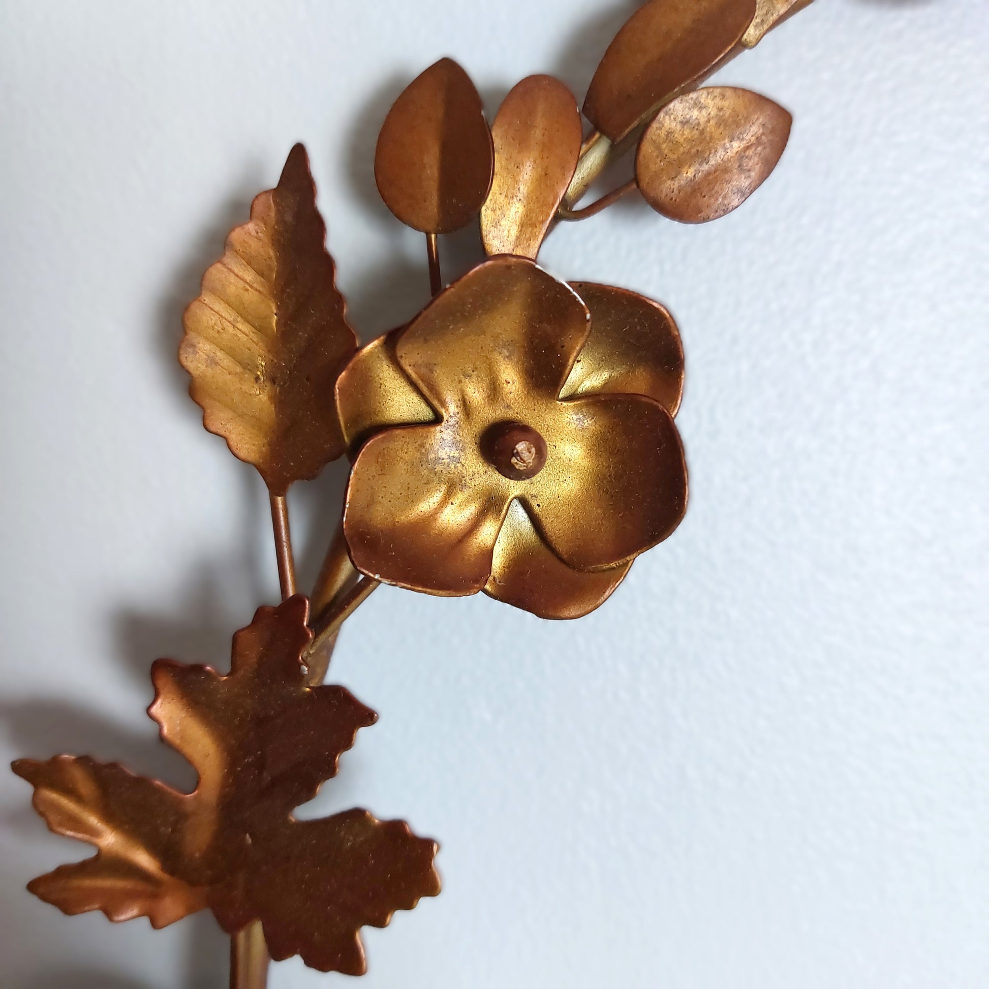 A close up of bronze style flowers and leaves against a pale background
