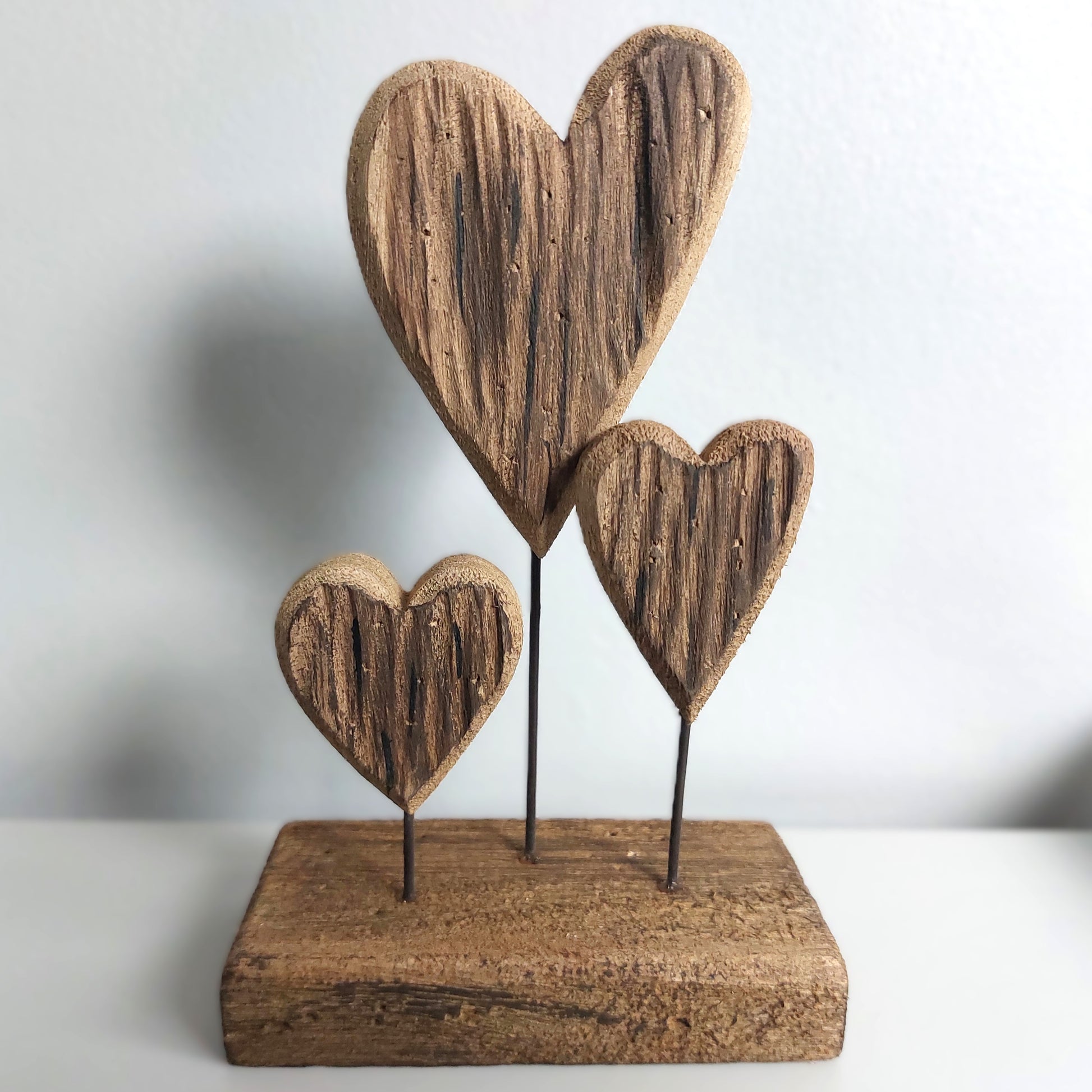 Wooden heart-shaped sculpture on a stand with a plain background