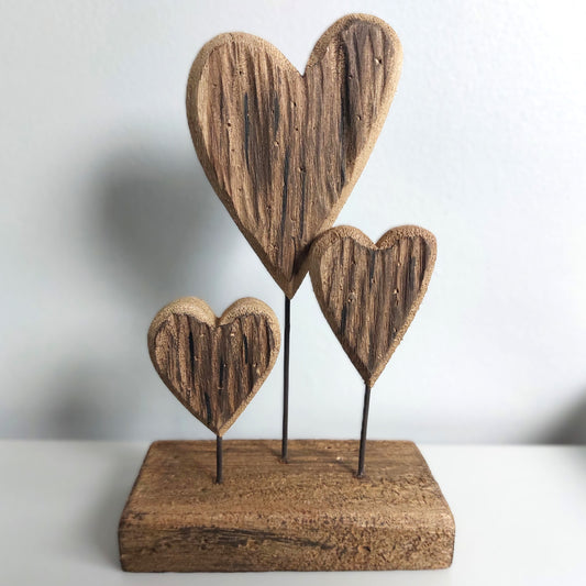 Wooden heart-shaped sculpture on a stand with a plain background