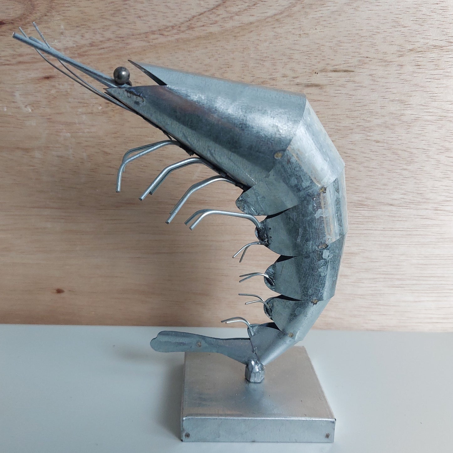 Metal sculpture of a shrimp on a wooden surface