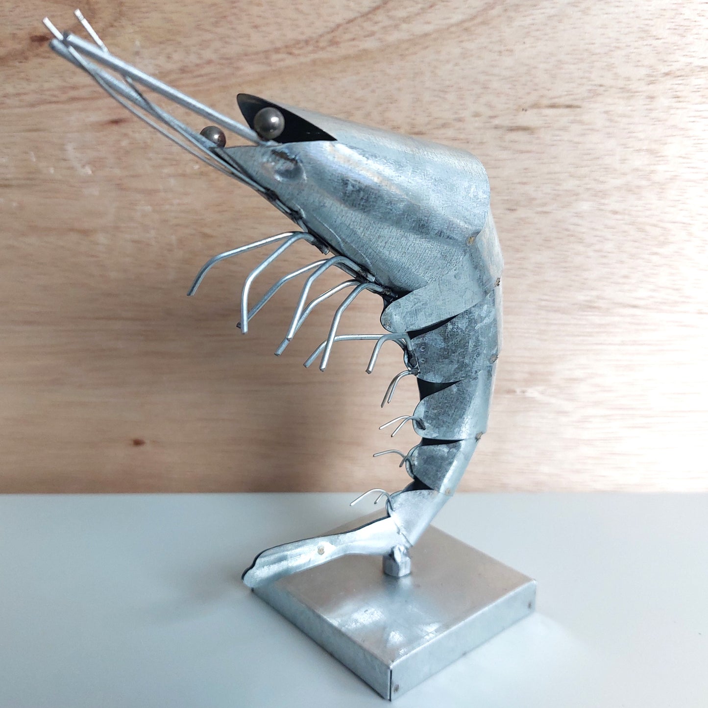 Metal sculpture of a prawn on a wooden surface