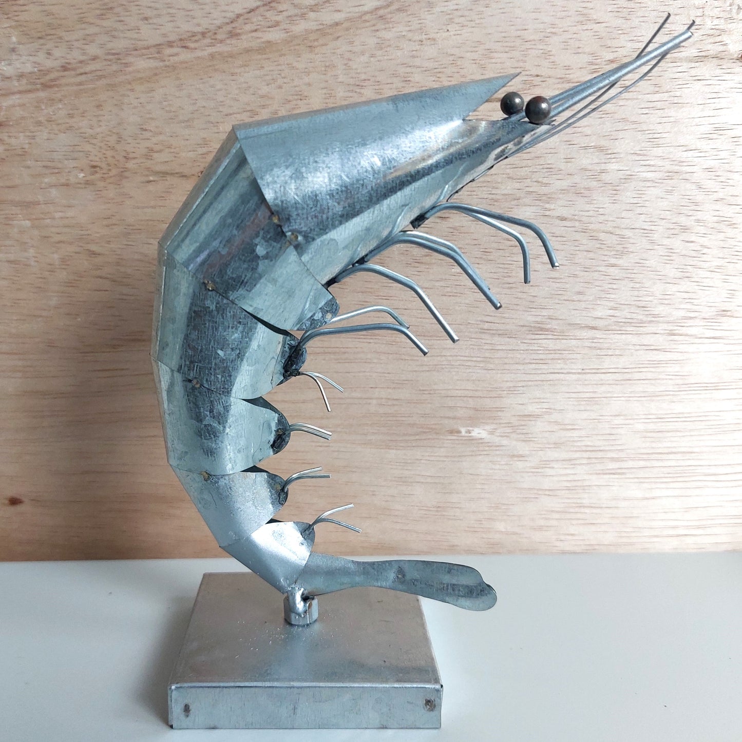 Metal sculpture of a shrimp on a wooden surface
