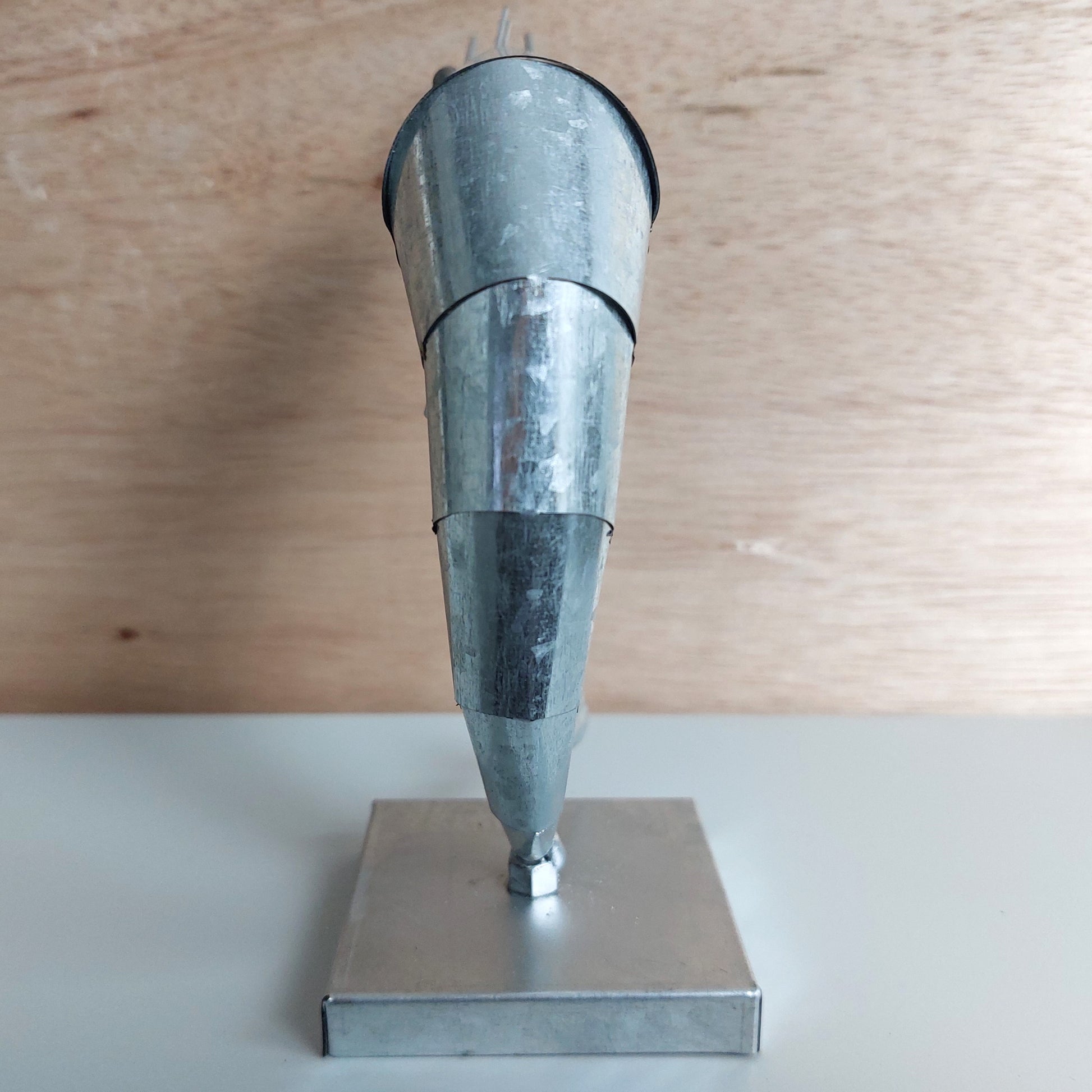 Metal prawn figurine on a square metal base against a wooden background