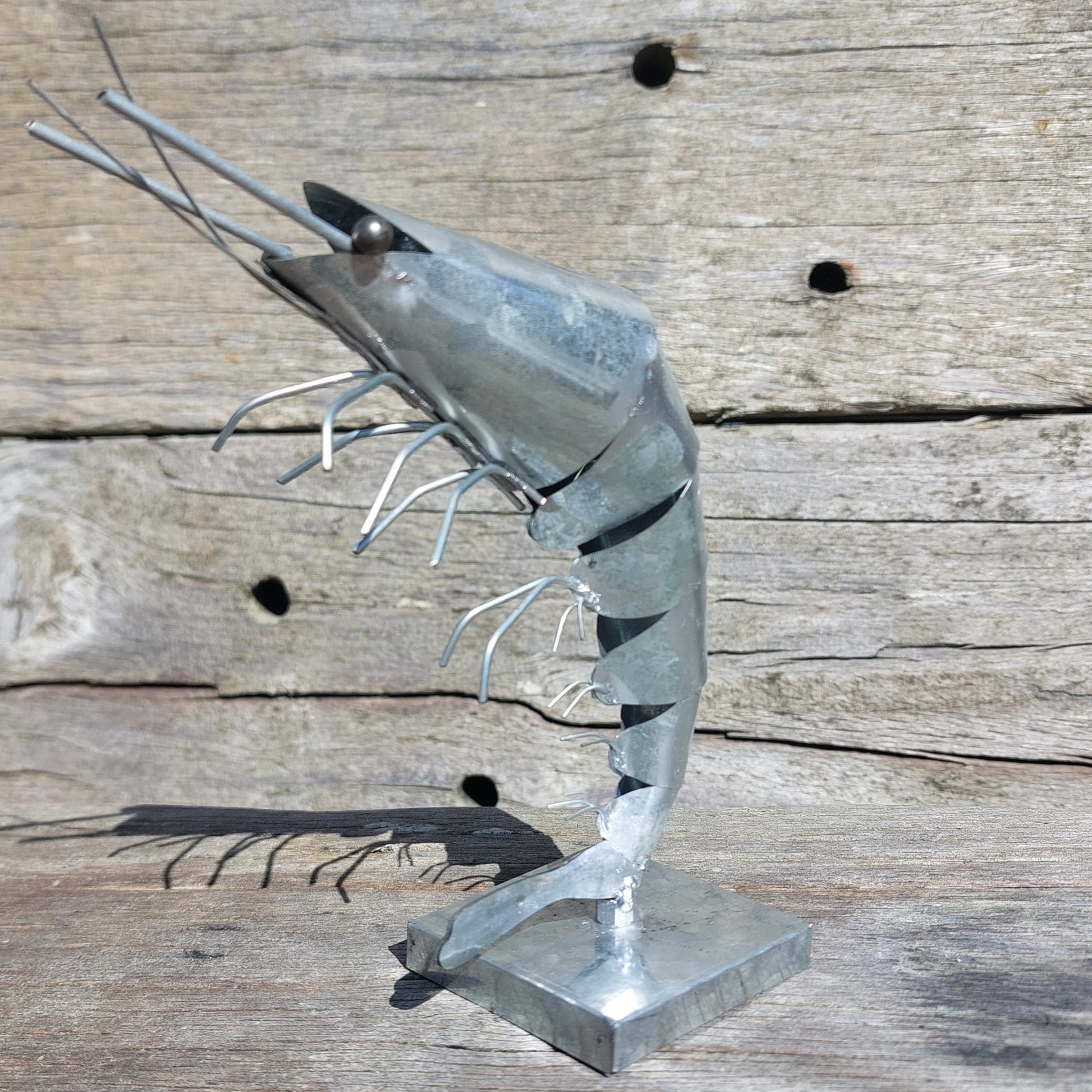 Metal steampunk sculpture of a shrimp on a wooden surface