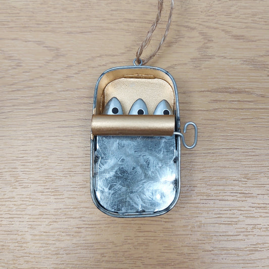 Small metallic decorative tin of sardines with a jute hanging string on a wooden surface