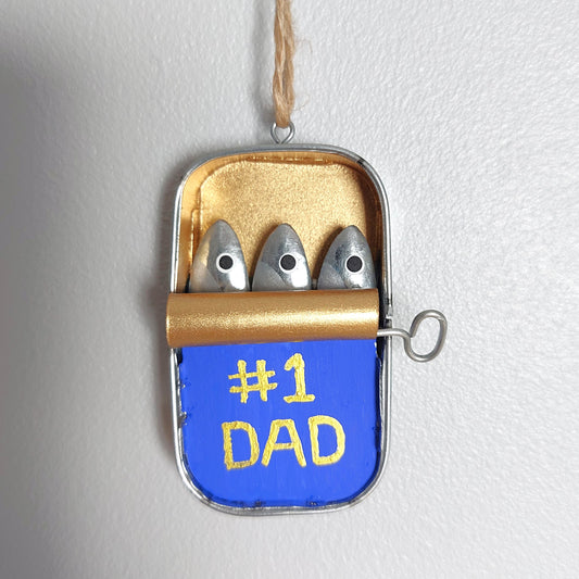 Decorative hanging ornamental tin with three silver fish inside labeled '#1 DAD' on a white background