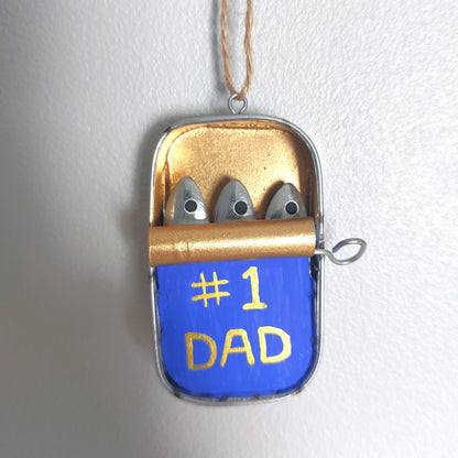 A hand painted small metal tin hanging decoration with metal sardines laying inside with a #1 Dad marking on the front of the tin