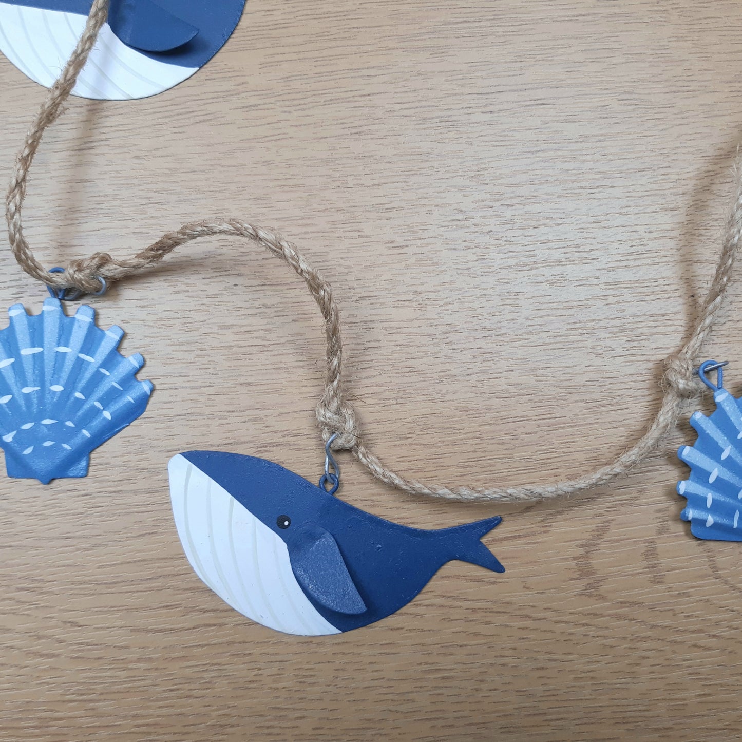 Decorative string with blue whale and scallop shell shapes on  a wooden surface