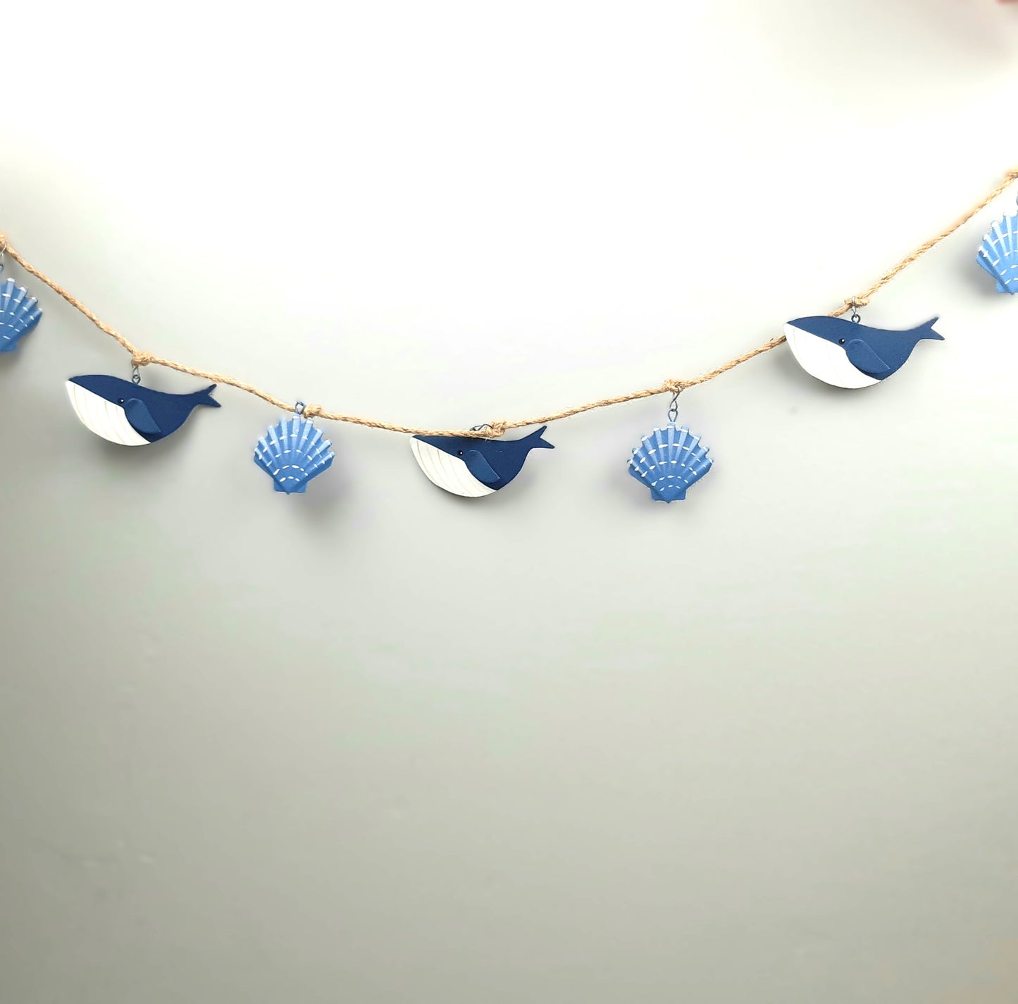 Decorative garland with whale and shell shapes on a plain background
