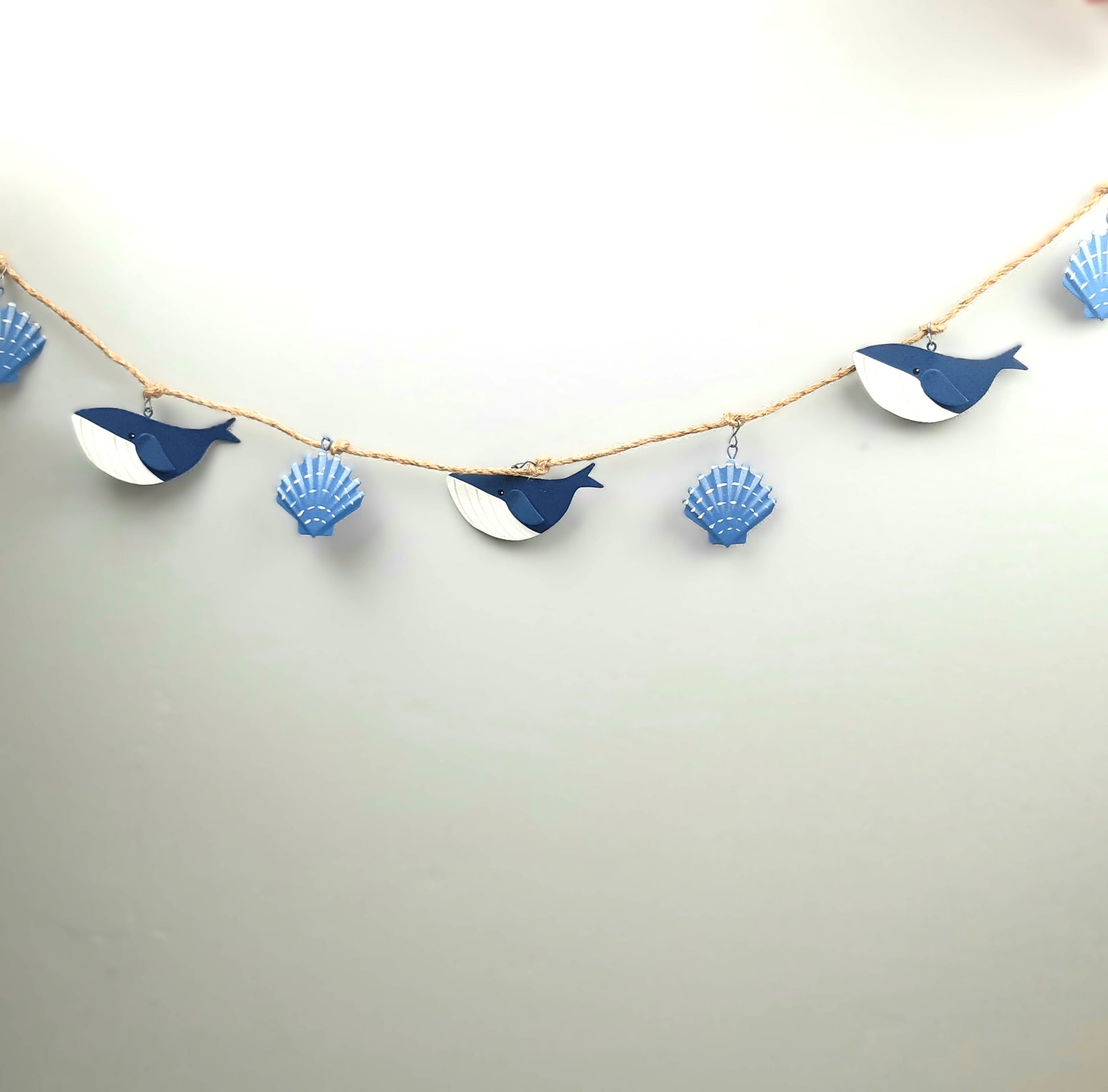 Decorative garland with whale and shell shapes on a plain background